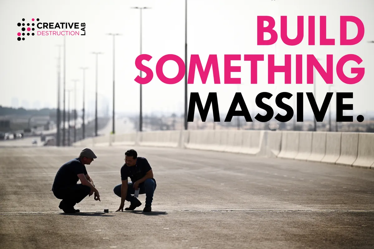 Two people crouch on a new, empty highway under the words “Build something massive”, Creative Destruction Lab’s programme image